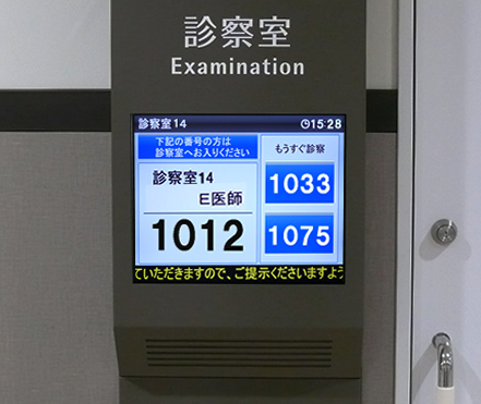 写真：診察室入り口のディスプレイに受付番号が表示されます。